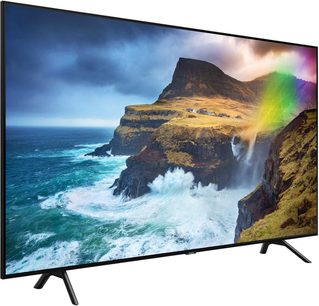 Samsung QE55Q70R-fladskærm, der viser en klippefyldt kyst ved havet med bølger, der bryder, og en regnbue