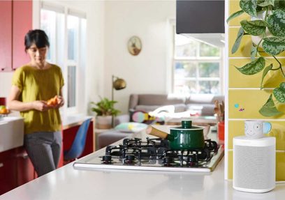 Trådløs tilsluttet Sonos One SL højttaler i hvid, set forfra i et køkken, ved siden af en komfur og grønne planter