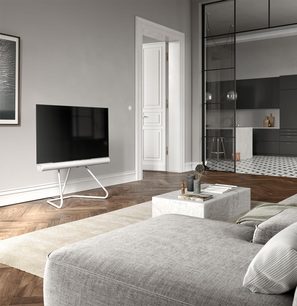 Lavt TV-møbel i lyst træ med skuffer, i en moderne stue med grå vægge, med sofa, tæppe og gulvstående TV