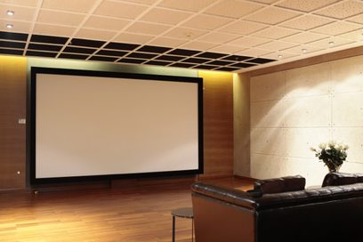 Vægmonteret Screen Excellence TAM 2 Enlightor 4K 160" projektionsskærm i et rum med læderlænestol og trægulv