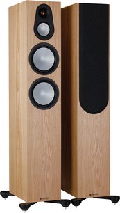 Kaksi Monitor Audio Silver 300 7G -lattiakaiutinta saarniviilulla, kolme pyöreää mustaa kaiutinelementtiä vaalealla puupinnalla etupuolella, kuvattu viistosti edestä