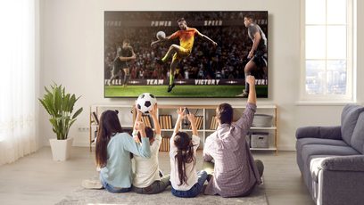 Billede af en fodboldkamp på et TCL 55QLED760 2022 TV, en familie på 5 personer sidder foran på en sofa
