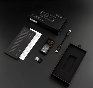 Korkean tarkkuuden kuuloke-esivahvistin M15i, ylhäältä katsottuna, läpinäkyvä kotelo, USB-C-kaapeli, USB-A-sovitin, musta laatikko, painetut asiakirjat