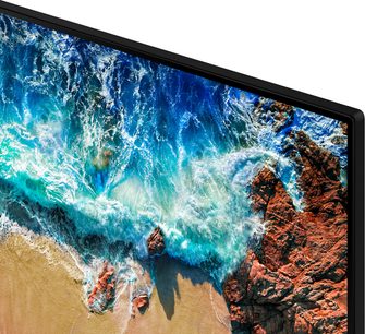 Samsung UE82NU8005-fjernsyn der viser et luftfoto af en strand med turkisfarvede bølger og rødlige klipper