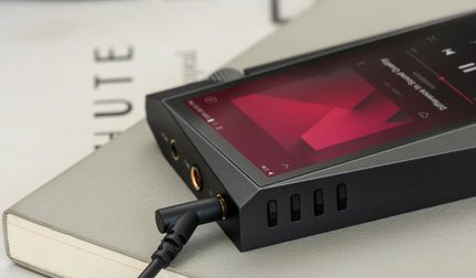 Black audiophile portable player with touchscreen displaying a red graph, close-up top view