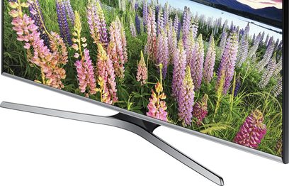 Samsung UE32J5500-fjernsyn, der viser lyserøde, violette og gule lupiner mod en baggrund af grønne grantræer