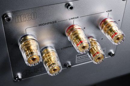 Pět zlatých šroubovacích audio konektorů na šedém elektronickém zařízení s nápisy "HECO", "HIGHPASS", "LINEAR", "+2dB", "LOWPASS", "BellaDonna"
