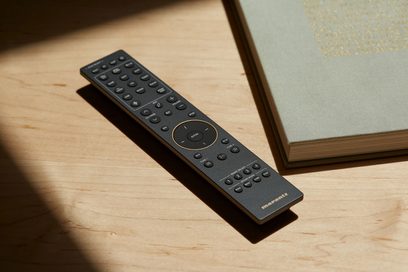Musta Marantz-kaukosäädin avoimen kirjan päällä, lähikuva ylhäältä päin vaalealla puupinnalla