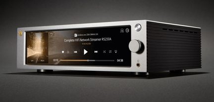 Мрежов hi‑fi плеър от сребрист алуминий, изглед отпред под три четвърти отдясно, екран, върток, изход за слушалки, черен оребрен страничен панел