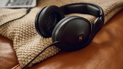 Sluten hi-fi-hörlurar Sennheiser HD 620S i svart med vadderade öronkuddar, ansluten ljudkabel, placerad på en tygyta