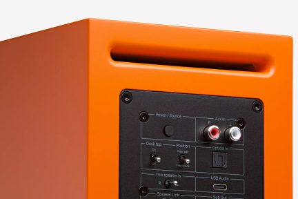Oranžový aktivní reproduktor, zadní pohled, černý připojovací panel s pomocnými RCA vstupy, optickým a USB audio vstupem