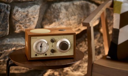 Træradio med lys farve, cremefarvet front, ur til venstre, stor indstillingsknap, højttaler på toppen, set fra tre kvart