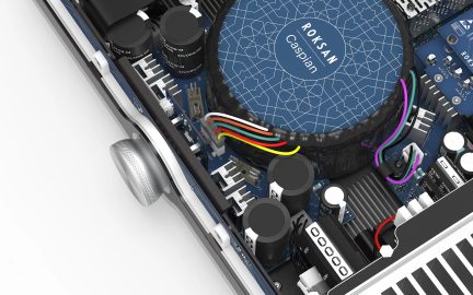 Pohled ze šikmého úhlu na elektronický obvod s modrým kruhovým transformátorem, černými kondenzátory, barevnými kabely a chladiči
