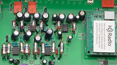 Nærbillede af det grønne printplademønster i en sort Rotel RT-12 netværksaudioafspiller med talrige elektroniske komponenter