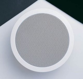 Rund indbygget højttaler fra Bowers & Wilkins CCM 65 i hvid, set forfra, med cirkulær sort perforeret grill i midten