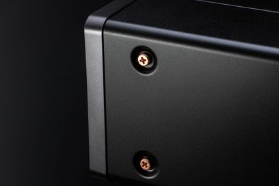 Зблизь на дві кріпильні гвинти з сріблястого металу на матовому чорному корпусі аудіопристрою Marantz CD60 сріблястого кольору