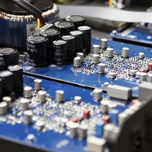 Blå printplade med sorte elektrolytiske kondensatorer i forskellige størrelser og overflademonteringmodstande