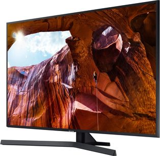 Samsung UE50RU7405-fjernsyn der viser et billede af en rød klippefyldt klippe med en åbning og en person der klatrer