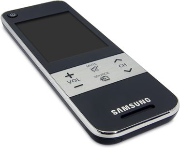 Univerzalni daljinski upravljalnik Samsung RMC30C2 črne barve z LCD zaslonom, gumboma za glasnost in vir, pogled od zgoraj na beli podlagi