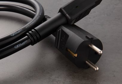 Nærbillede af et QED XT5 Power 3m strømkabel med europæisk hanstik på en grå overflade