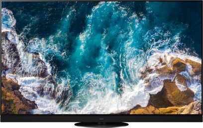 Panasonic TX-55HZ1500E-tv, der viser et billede af turkise, brusende bølger og hvidt skum på brune klipper, set forfra