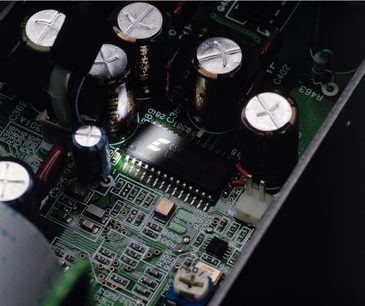Nærbillede af indersiden af en sort Onkyo C-733 CD-afspiller, der viser mekanikken og de elektroniske komponenter på printpladen