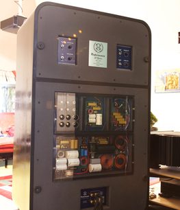 Mørkegrå elektrisk vægboks set forfra i åben tilstand med elektroniske komponenter, displays og farvede kontakter indeni