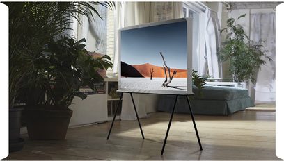 Samsung The Serif QE65LS01BB 2022 TV på sort metalfod, der viser et ørkenlandskab med døde træer