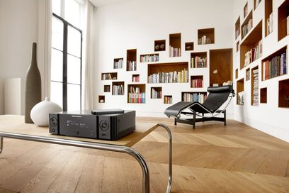 Vysokofidelitní "all-in-one" systém Marantz MCR-510 v černé barvě v obývacím pokoji s knihovnou, křeslem a dřevěným konferenčním stolkem