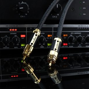 Zbliżenie na dwa wtyki RCA kabla koncentrycznego Oehlbach Black Connection digital 2m, czarna teksturowana osłona z polimeru i pozłacane metalowe złącza, prezentowane przed sprzętem audio