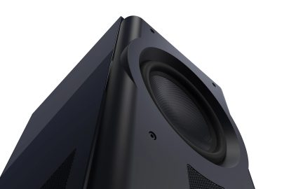 Low-angle view of a black subwoofer with a circular speaker, rounded corners, and perforated side grilles