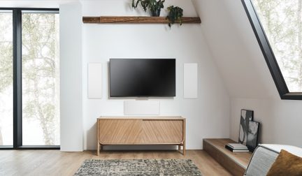 Mobile TV scandinavo in legno chiaro sotto schermo piatto a parete in salotto mansardato moderno