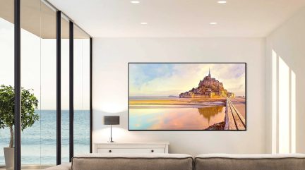 Obrázek zachycující Mont-Saint-Michel při západu slunce, odrážející se ve vodě, zavěšený v moderním interiéru