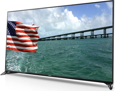 Panasonic TX-65CX800 65-inch TV displaying an American flag waving in front of a multi-span bridge over water