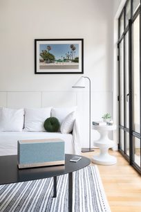 Moderne stue med hvid sofa, sort sofabord, hvid lampe, sort-hvidt tæppe og indrammet fotografi af en palmelandskab