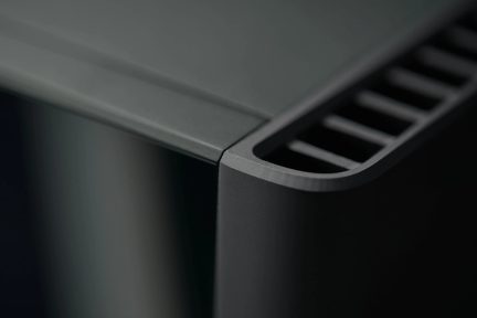 Vedere de aproape a colțului superior al carcasei negre mate cu grilă de ventilație orizontală și suprafață netedă