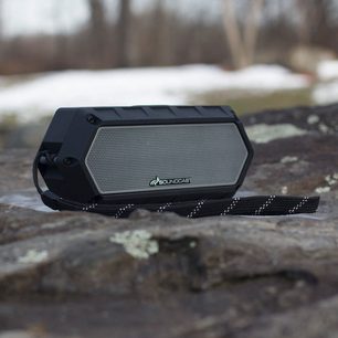 Soundcast VG1 sort, bærbar højttaler, set forfra i nærbillede på et trægulv, med sort flettet rem