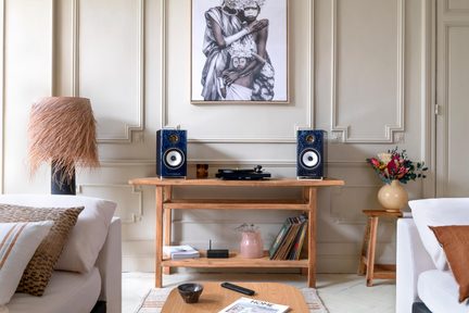 Par blå Triangle bokhyllehögtalare med vit högtalare på trämöbel och vinylspelare