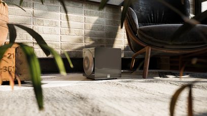 Subwoofer SVS 3000 Micro negru lucios, vedere frontală, așezat pe un covor, lângă un fotoliu de piele maro