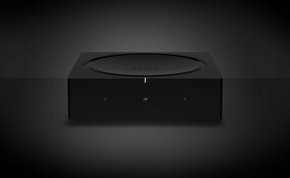 Čierny stereo hi-fi zosilňovač Sonos Amp, pohľad spredu mierne zospodu, predná strana s tlačidlami a kontrolkami, zaoblený obdĺžnikový tvar