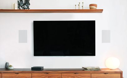 Televisão de tela preta em móvel de madeira com prateleira, objetos decorativos, planta verde em vaso branco