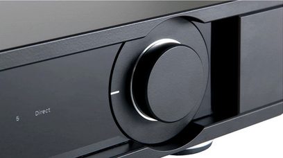Bouton rotatif en métal noir brillant sur un panneau noir mat, vu de face en gros plan