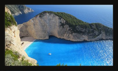 L'immagine mostra un'insenatura mediterranea dalle acque turchesi circondata da ripide scogliere rocciose, con una piccola barca in lontananza