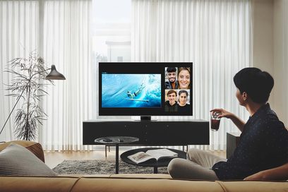 Televizor Samsung QE55QN85B 2022 zobrazující 4 tváře na obrazovce, umístěný na černém TV nábytku v obývacím pokoji s bílými závěsy