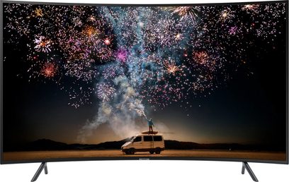 Televizor Samsung UE55RU7305 zobrazující barevný ohňostroj explodující na noční obloze nad dodávkou zaparkovanou v poušti