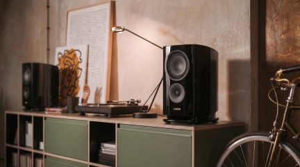 Sortlakeret sort Canton-reolhøjttaler med buet front på hi-fi-møbel med pladespiller i en moderne stue