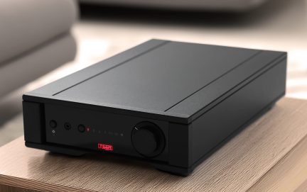 Black rectangular case with a circular button, red indicator lights, and connectors on a wooden surface