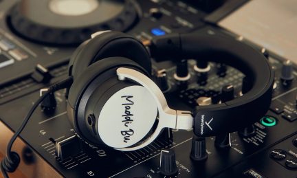 Sort circumauralt headset i metal og plast, polstret hovedbøjle, sølvfarvede gafler, ørekop med indskrift, på DJ-konsol