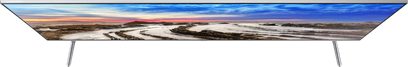 Frontvy av Samsung UE55TU7005 TV, platt skärm som visar ett ökenlandskap med en sjö som speglar en färggrann molnig himmel vid solnedgången