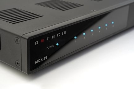Čierne obdĺžnikové zariadenie s mriežkami na vrchu, predným panelom s modrými očíslovanými kontrolkami a textom "MDX-12".